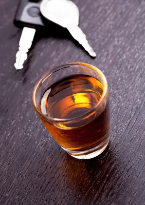 Car keys next to a glass of alcohol