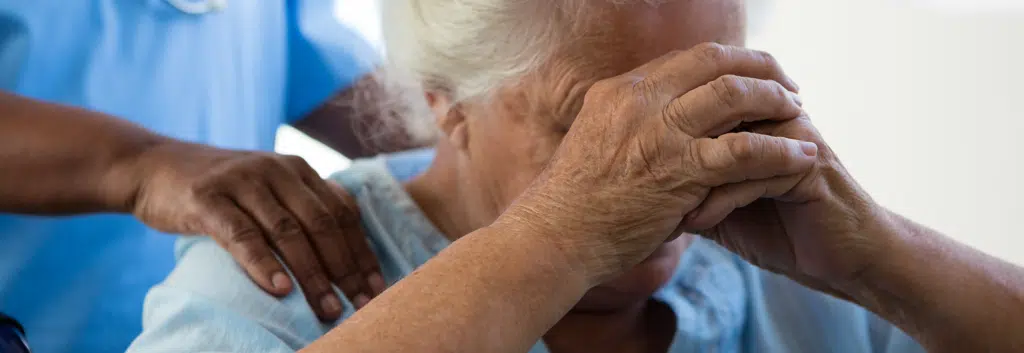 Elderly woman with hands folded on face