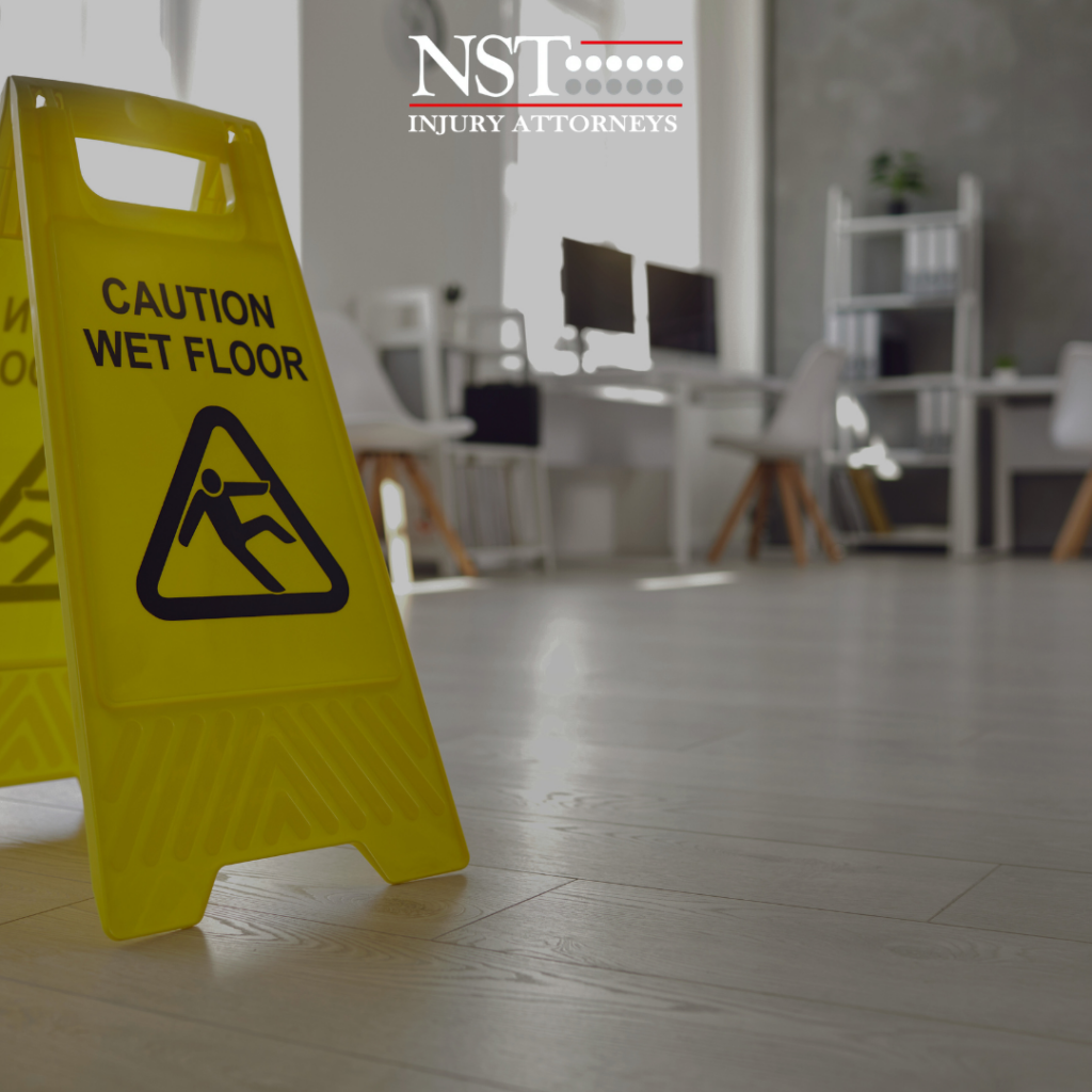 Photo of a wet floor sign with the NST Law logo