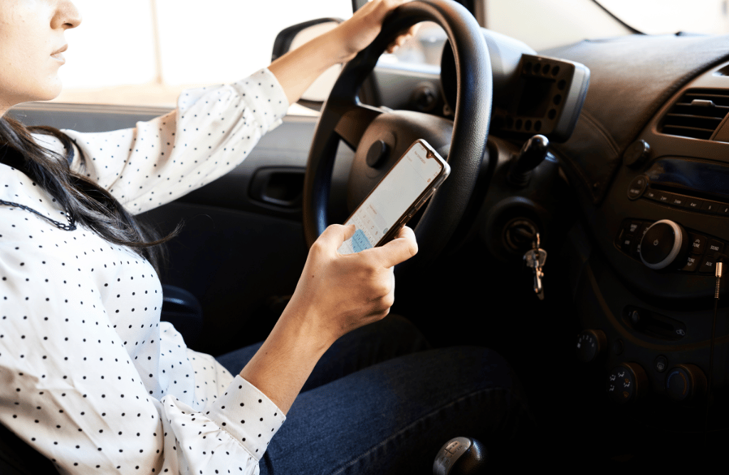 A lady driving and using her phone