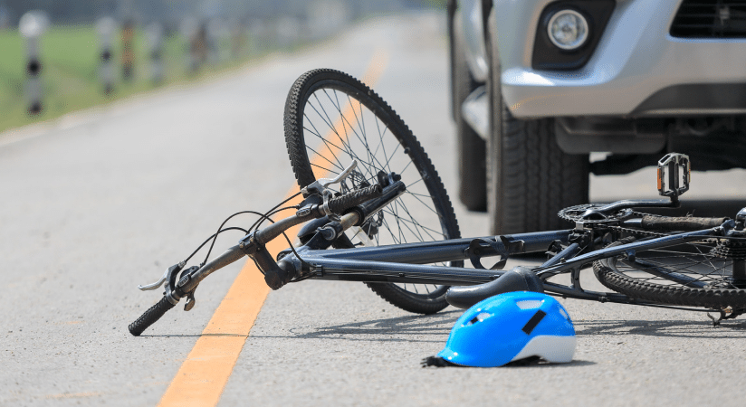 A fallen bicycle and helmet in front of a car