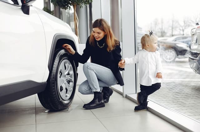 Mom looking at car with child