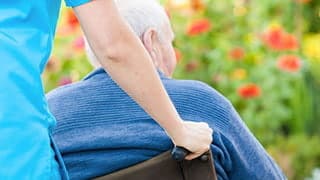 Nursing home pushing elder man in wheelchair